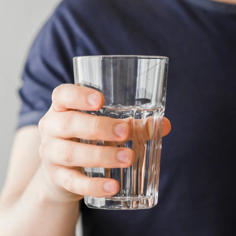 Hand houdt een glas helder, gefilterd drinkwater vast