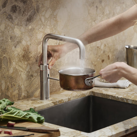 Quooker kokendwaterkraan in gebruik — kokend water wordt direct in een pan geschonken in een moderne keuken